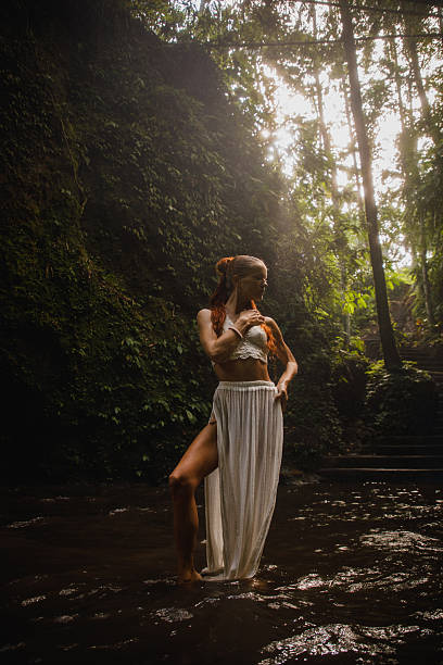 istock Woman in white standing in serene jungle stream 2234885135