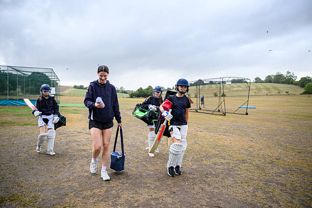 istock Coach walking off field with young female batsmen after practice 2234886776