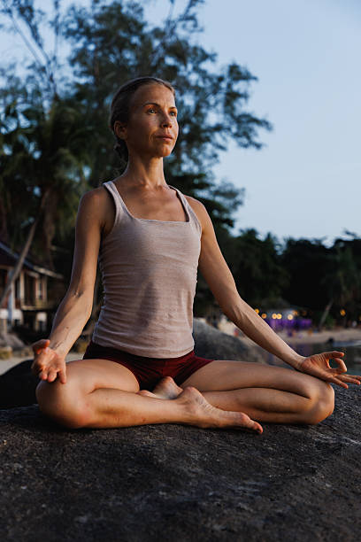 istock Woman meditating outdoors seated on a rock during peaceful evening 2234888687