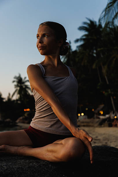 istock Woman practicing yoga outdoors at sunset with tropical background 2234888707