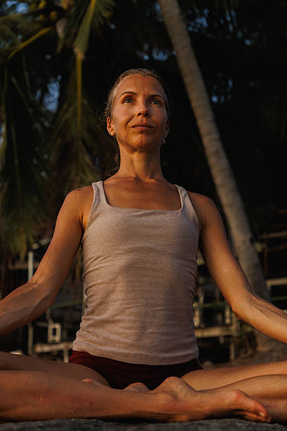 Woman practicing yoga in tropical outdoor setting at sunset
