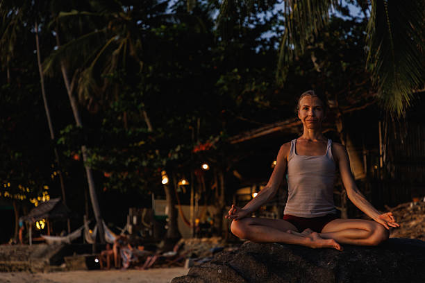 istock Woman practicing meditation outdoors surrounded by a tropical beach setting 2234888723