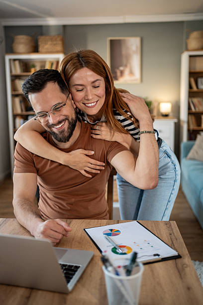 istock Happy couple embracing while working from home on laptop 2234889402