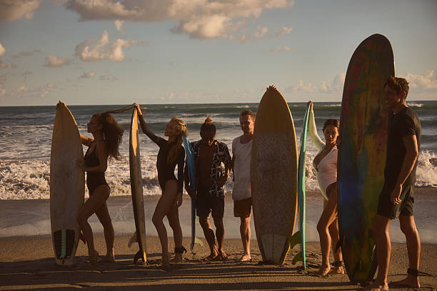 istock Group of surfers posing with surfboards on a beach during sunset 2234890976