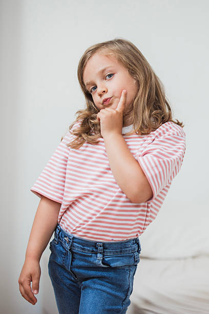 Portrait of a pensive young girl contemplating a choice, touching her cheek with her index finger
