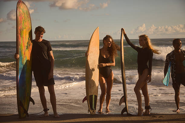 istock Friends holding surfboards on the beach on a sunny day 2234893791