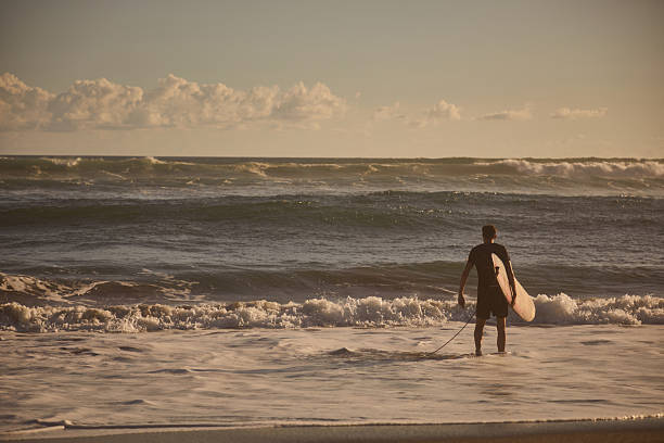 istock Person with surfboard on the shoreline preparing for surfing 2234894195