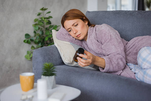 istock Sick young woman lying on sofa reading medicine instructions 2234894893