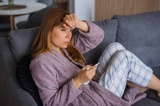 istock Sick young woman feeling unwell, checking her temperature on the sofa 2234895053