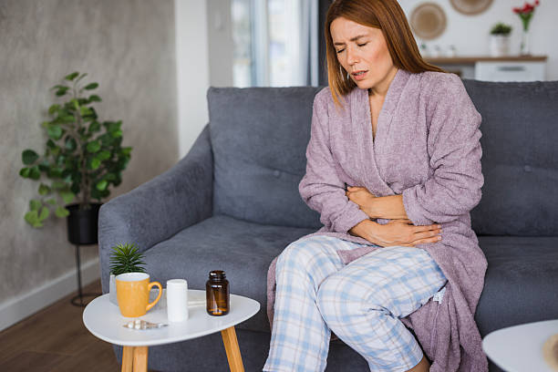 istock Woman suffering from abdominal pain while sitting on sofa at home 2234895075