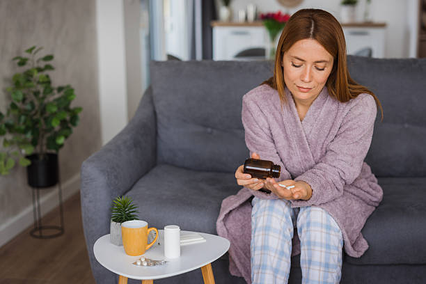 istock Sick woman taking pills at home on sofa 2234895128