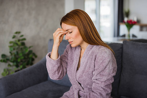 istock Woman suffering from strong headache at home sitting on sofa 2234895129