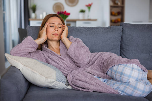 istock Woman suffering from strong headache lying on sofa at home 2234895321
