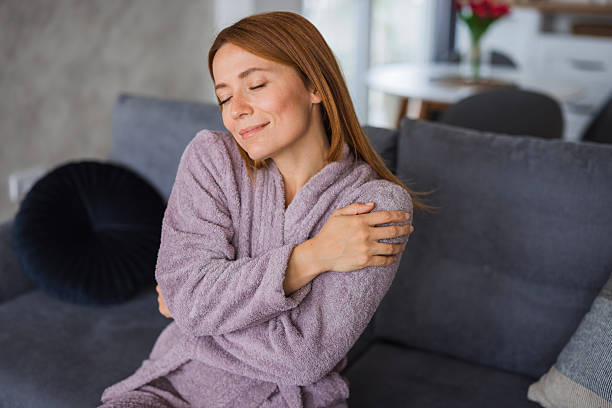 istock Serene woman embracing herself on sofa in bathrobe, feeling cozy and relaxed 2234896436