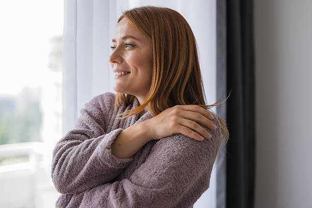 istock Serene woman wearing bathrobe enjoying morning view from window 2234897198