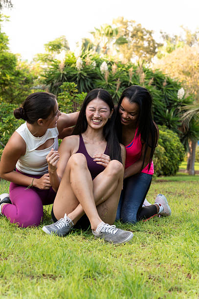 istock Three young women laughing together after exercising in a park 2234897491