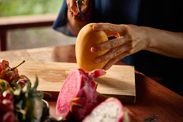 istock Person slicing mango with fresh fruits in a vibrant kitchen setting 2234898627