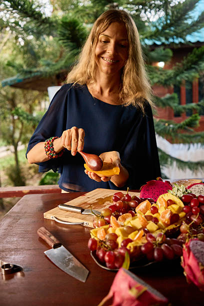 Smiling Woman Preparing Fresh Fruits on a Rustic Outdoors Wooden Table