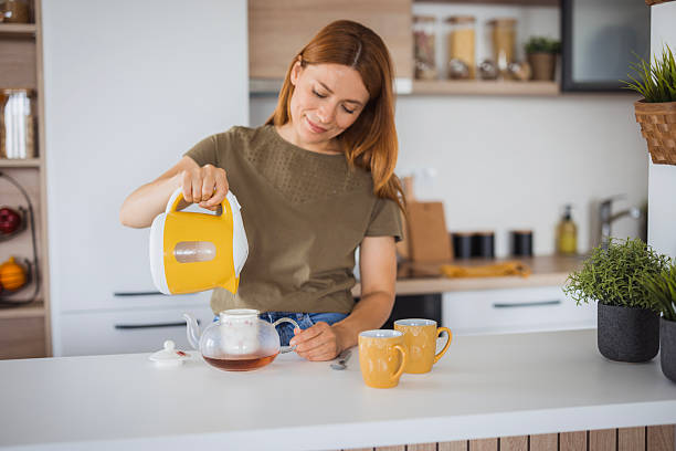 istock Smiling woman preparing tea in her modern kitchen 2234899113