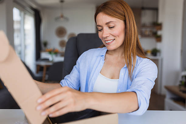 istock Happy woman opening a package at home 2234899612