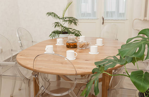 istock Cozy dining setting featuring a round wooden table surrounded by transparent chairs, complemented by lush green potted plants, creating a warm and inviting interior atmosphere. 2234900225