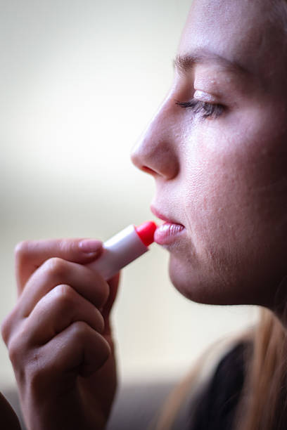 Blonde woman is using lipstick, close-up make up.