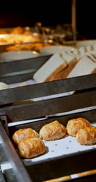 Freshly baked croissants and bread displayed on bakery shelf, warm