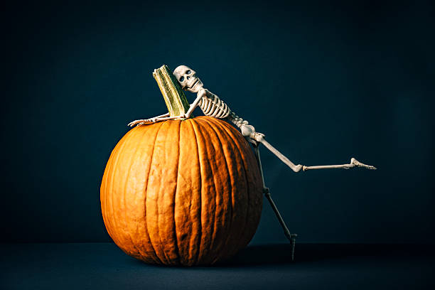 Autumn and halloween 2022. Fall flower , pumpkin and squash arrangement with spider skeleton. Many varieties of flowers an squashes on orange background. Minimal composition.