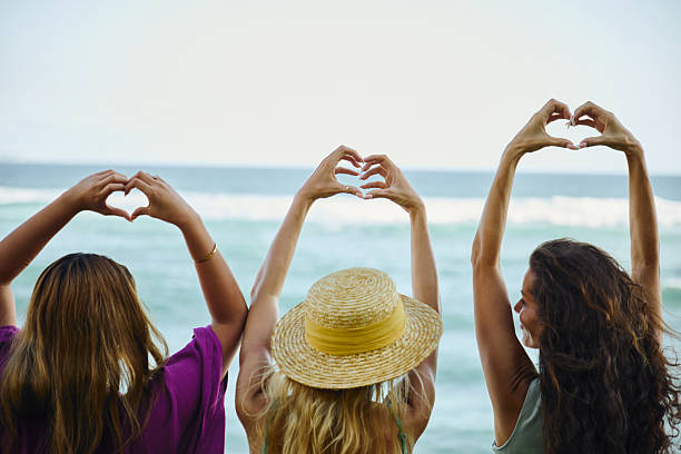 istock Three friends making heart shapes with their hands at the beach 2234905397