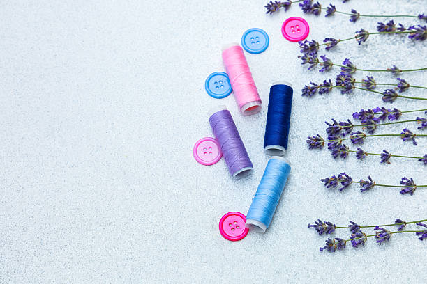 istock Colorful sewing thread and buttons with lavender flowers on a textured background 2234905493