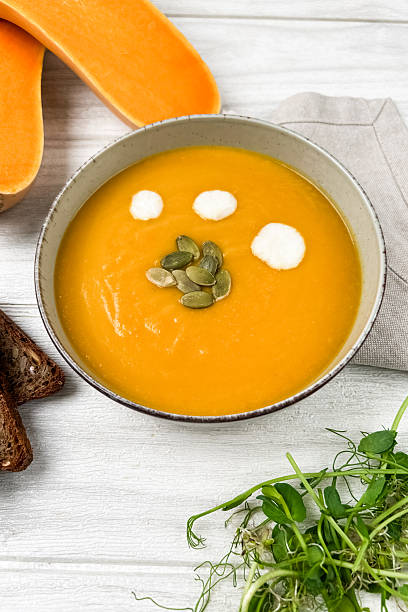 Butternut squash soup with garnishes on a rustic table setting in the afternoon