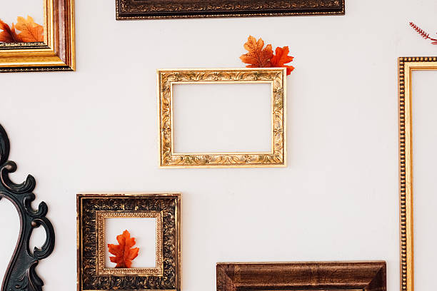 istock Collection of vintage picture frames with fall leaves displayed on a white wall 2234905775
