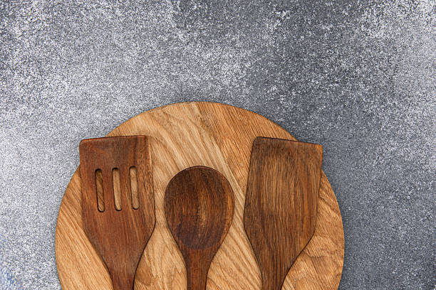 istock Wooden kitchen utensils arranged on a round wooden board on a gray surface 2234906241