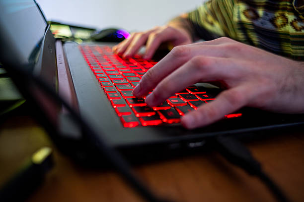 istock Close-up of hands typing on laptop keyboard with red lights 2234906414