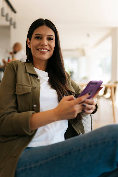 istock Young woman using mobile phone in a restaurant and smiling at camera 2234908134