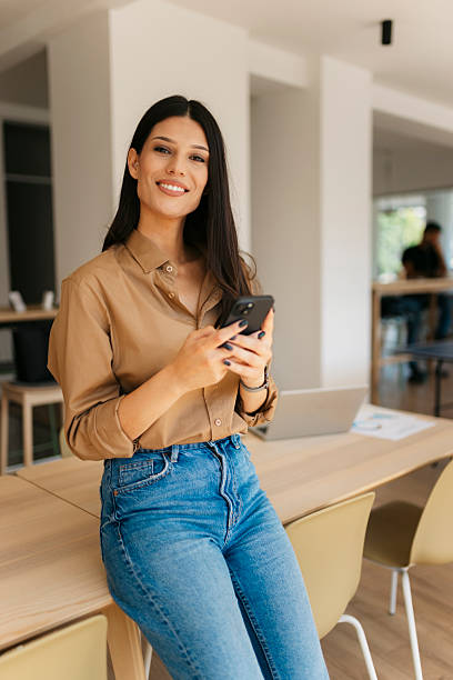 istock Smiling businesswoman using smartphone in modern office 2234909003