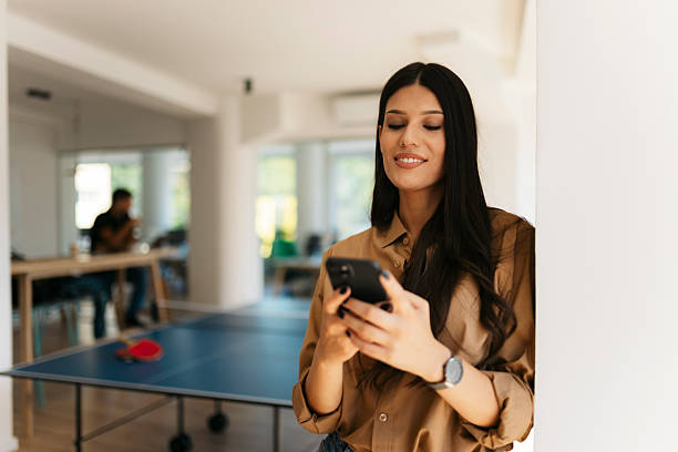 istock Young businesswoman using smartphone in modern office with ping pong table 2234909017