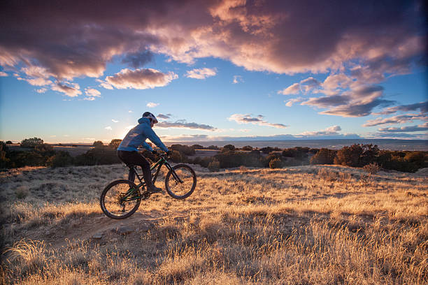 Mature, male, mountain biker following desert track along ridge crest at sunrise, White Ridge Area, Albuquerque New Mexico