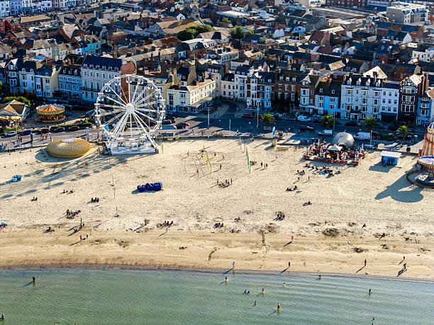 Felixstowe beach showing traditional huts, seafront buildings, and breakwaters with a cloudy sky