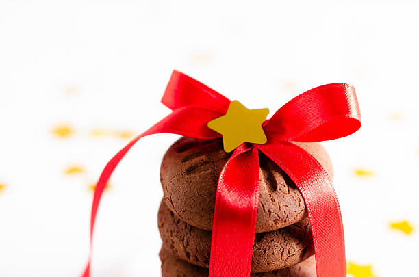 Stacked chocolate cookies tied with a red ribbon and a golden star on the top. Horizontal format and copy space.