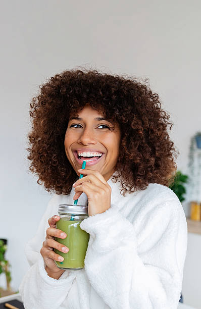 Young mixed race woman drinking healthy green juice at home