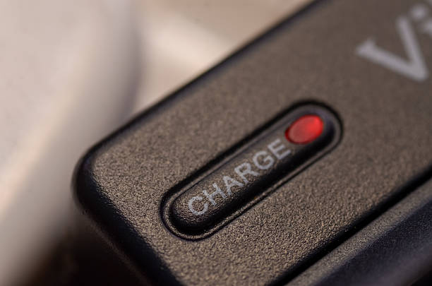 a black electronic device with an illuminated red LED light next to the embossed word CHARGE on a textured panel.