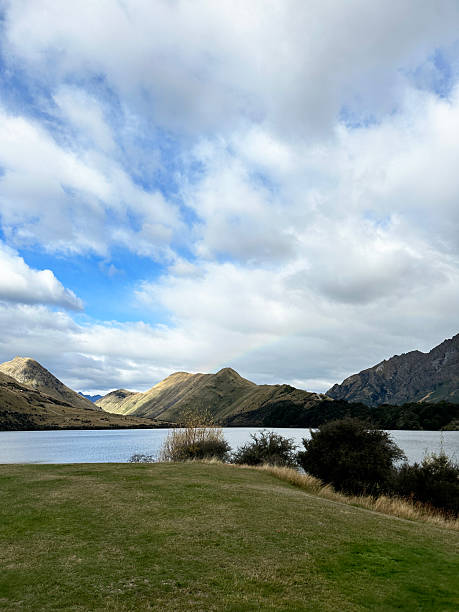 istock Serene mountain lake under cloudy sky with rolling hills and lush grass 2234920368