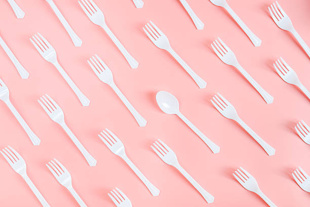 istock Many white plastic forks with one spoon lie diagonally on a light pink background 2234927994