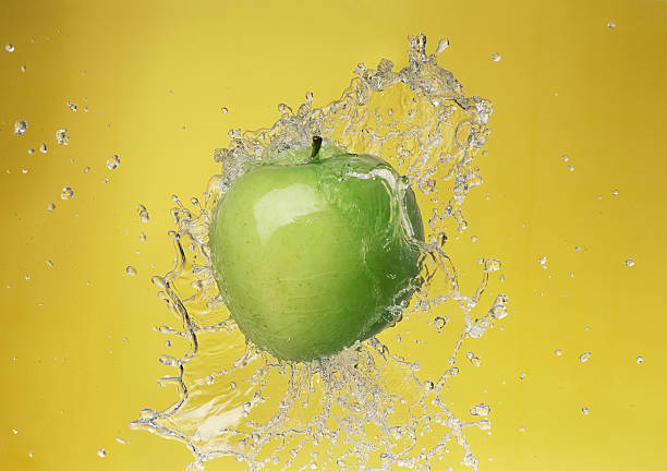 istock Apple in water splashes on yellow back 2234939829