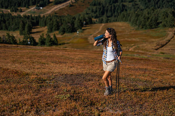 Hiker woman drinking water on a mountain while taking a break from a hike at a beautiful view.