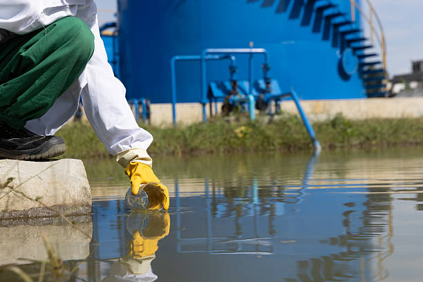 istock Young science Biologist or environmental quality inspector wearing protective gear and white lab coat collecting water sample from Sedimentation pond , water treatment facilities 2234943963