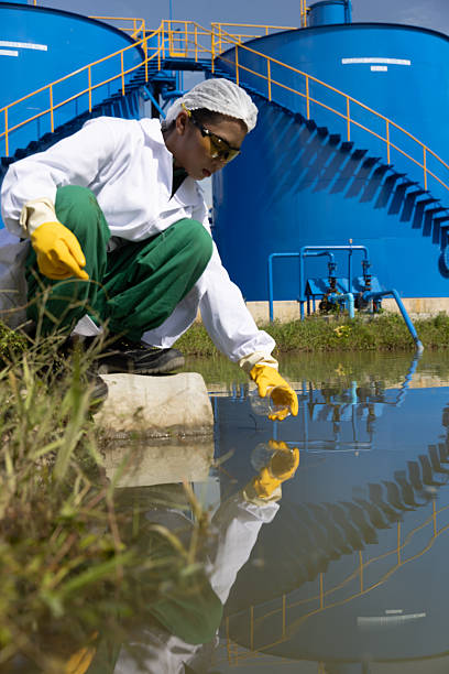 istock Young science Biologist or environmental quality inspector wearing protective gear and white lab coat collecting water sample from Sedimentation pond , water treatment facilities 2234943968