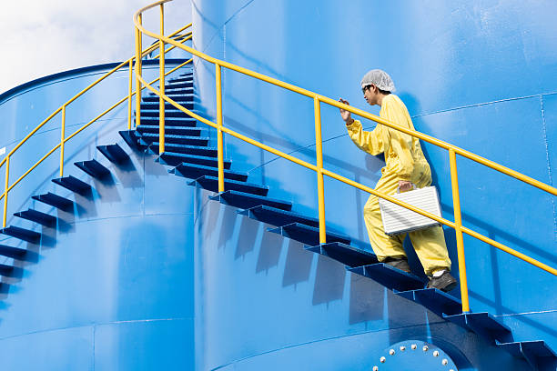 istock Water analysis or science in green and yellow protective clothing handle lab test equipment step up staircase of huge industrial Pulsator Clarifier Tank 2234944040