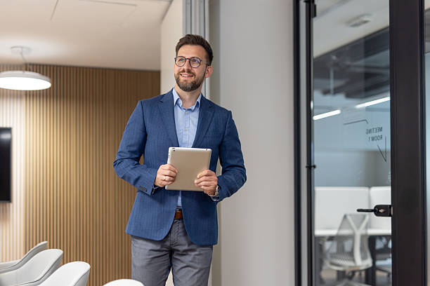 istock Businessman walking through modern office holding digital tablet 2234948603